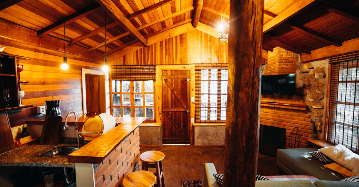 Interior de cabaña de madera con ventanal amplio hacia el bosque